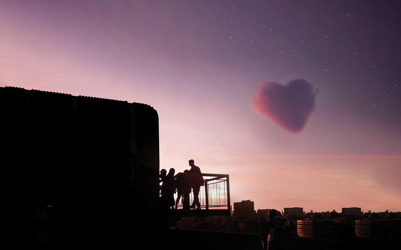 ID: the silhouette of a small group of people is seen standing on a raised platform against the London skyline and a warm purple sunset with a single pink cloud in the form of a heart passing by above.